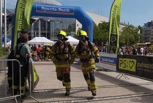 Zwei Feuerwehrleute laufen in Schutzausrüstung.